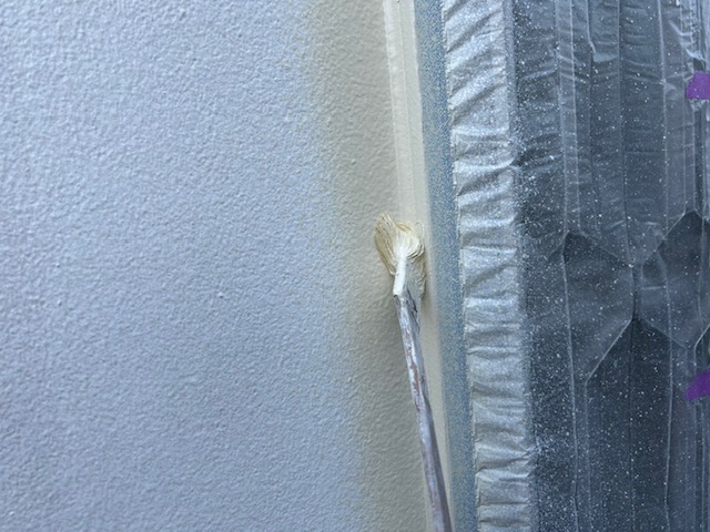 養生したサッシの際を刷毛で塗り込んでいるところ