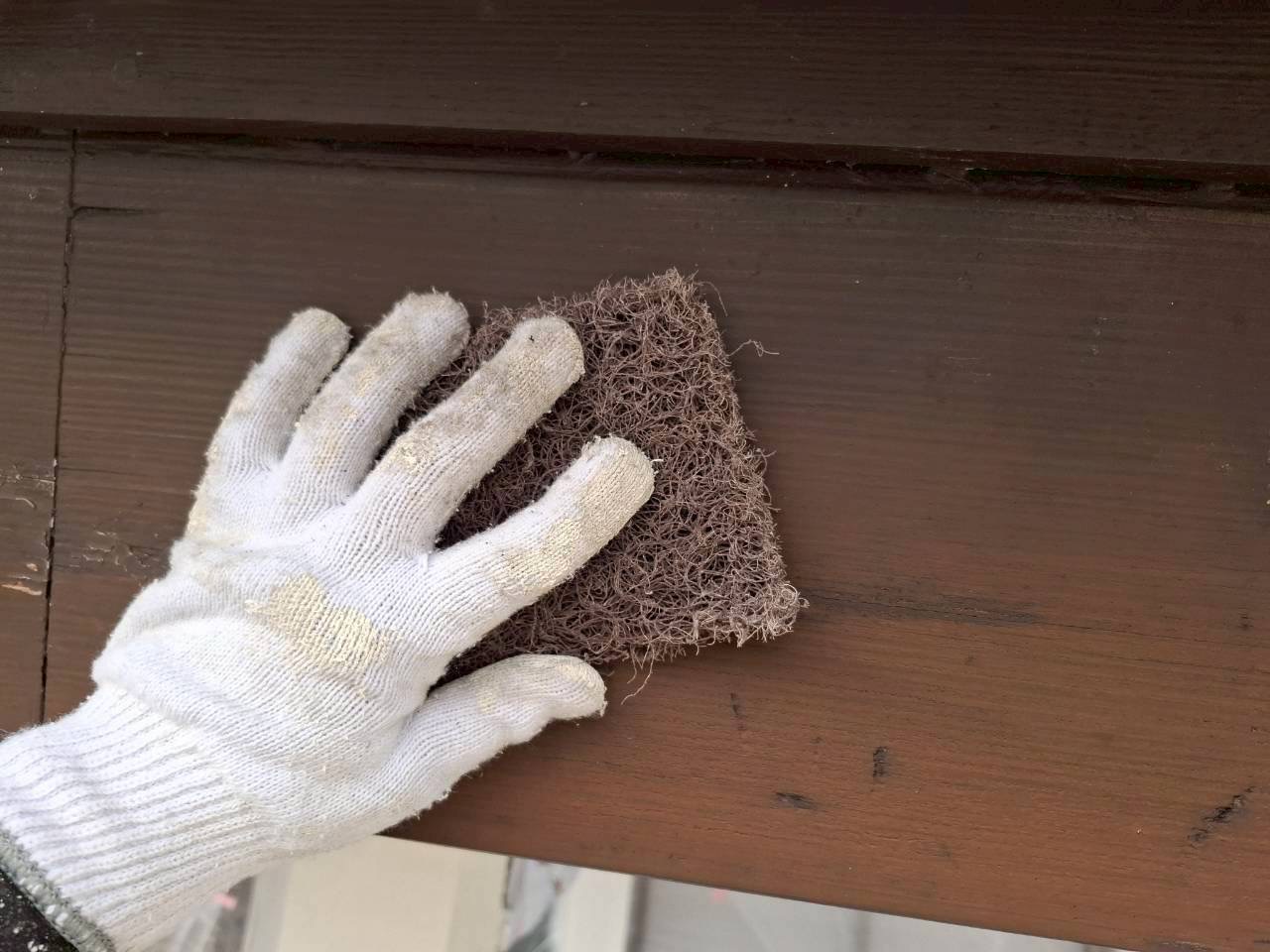 伊賀市U様邸の破風板、茶色の古い塗膜が残る面をマジックロンでケレンしている様子