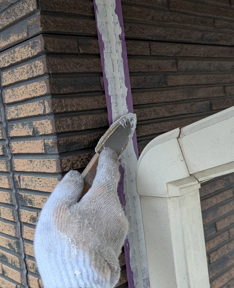 ヘラでシーリング材を押さえて圧着させる仕上げ作業