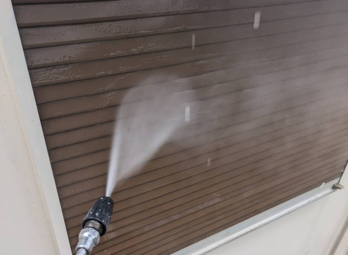 茶色のシャッターを高圧洗浄で洗う様子